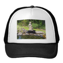 Chat noir sous la statue dans le jardin vert casquette