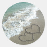 Deux coeurs de sable sur la plage, océan romantiqu autocollants ronds