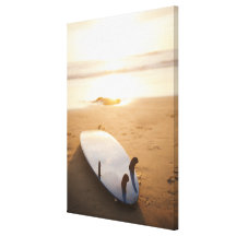 Planche de surf s'étendant sur la plage au coucher impressions sur toile