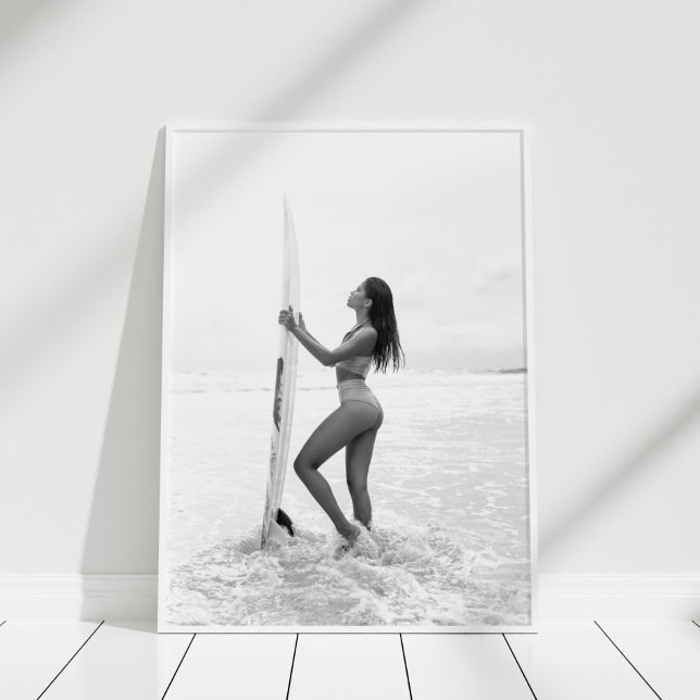 Affiche Fille de surfeur noire et blanche sur la plage (Black and White Surfer Girl on the Beach Poster in white frame on wooden floor.)