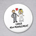 Aimant Couple mariage - Sous la nouvelle gestion<br><div class="desc">Un joli dessin d'un couple marié sous-titré "sous la nouvelle direction". Est-ce la mariée ou le marié qui porte le pantalon dans le mariage ? Idéal pour un cadeau mariage,  ou pour porter en lune de miel.</div>
