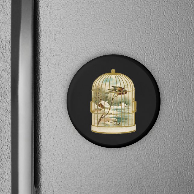 Aimant Oiseau Dans La Scène D'Hiver De Cage (Golden birdcage with winter cabin scene inside bird on branch on black round magnet.)