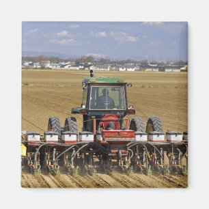 Aimant Tracteur tirant un semoir de maïs semence.