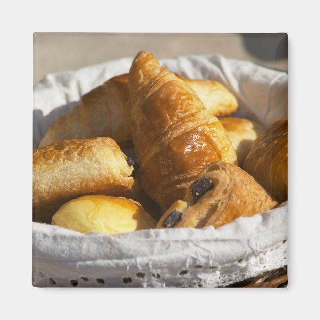 Aimant Un panier petit-déjeuner en osier avec croissants. (Devant)