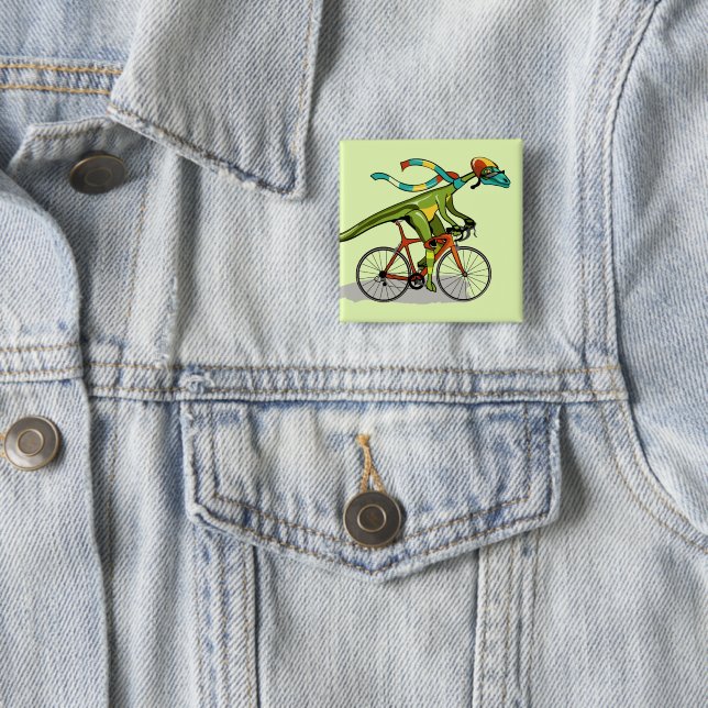 Badge Carré 5 Cm Un Dinosaure Anabisetia À Vélo. (En situation)