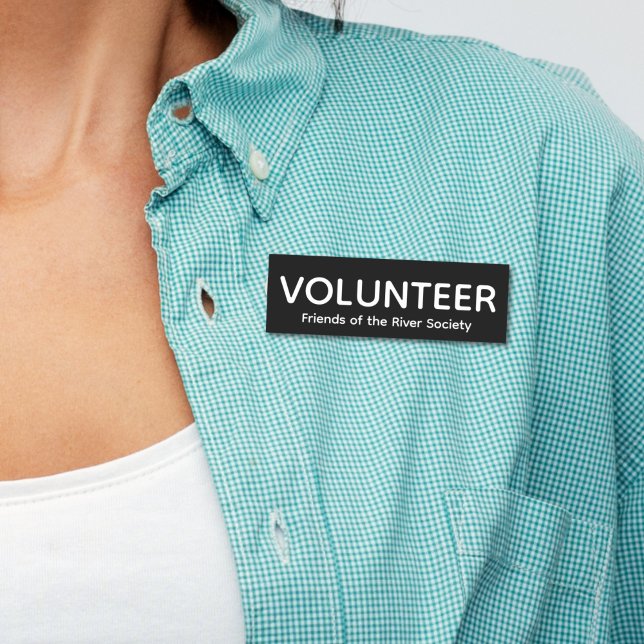 Balise de nom de badge de bénévolat simple (Woman in blue shirt wearing this customizable volunteer name tag badge with white letters on black.)