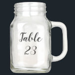 Bocal Mason Rustic Mason Jar Numéro de table Mariage Noms<br><div class="desc">Ces Mason Jar double comme pièce centrale de table avec le numéro de table et le nom des invités sur le dos dans un design rustique avec script de calligraphie whimsical. Remplissez-le de fleurs et utilisez-le pour votre mariage,  douche nuptiale,  wedding shower,  fête d'anniversaire ou toute autre célébration.</div>