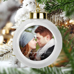 Boule En Céramique Premier Noël Engagé Photo Blanc Moderne<br><div class="desc">Commémorez votre fiançailles avec ce magnifique ornement de gardien moderne. Le texte blanc dit "Notre premier Noël engagé", avec le mot "engagé" dans un élégant script de calligraphie avec des échasses décoratives avant et après. Remplacez l'exemple d'image par votre photo préférée, et ajoutez vos noms et l'année. Un filtre dégradé...</div>