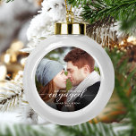 Boule En Céramique Premier Noël Engagé Photo moderne Script blanc<br><div class="desc">Commémorez votre fiançailles avec ce magnifique ornement de gardien moderne. Le texte blanc dit "Notre premier Noël engagé", avec le mot "engagé" dans un élégant script de calligraphie avec des échasses décoratives avant et après. Remplacez l'exemple d'image par votre photo préférée, et ajoutez vos noms et l'année. Un filtre dégradé...</div>
