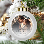 Boule En Céramique Premier Noël Engagé Photo personnalisée Gris Scrip<br><div class="desc">Commémorez votre fiançailles avec ce magnifique ornement de gardien moderne. Le texte en gris fusain dit "Notre premier Noël engagé", avec le mot "engagé" dans un script élégant avec des swashes avant et après. Remplacez l'exemple d'image par votre photo préférée, et ajoutez vos noms et l'année. Un filtre dégradé blanc...</div>