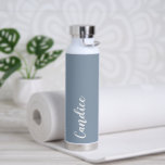 Bouteille D'eau Dusty Blue Mariage personnalisé Bridesmaid<br><div class="desc">Offrez votre femme de chambre ou femme d'honneur mariage avec cette bouteille d'eau isolée à la mode et vide qui porte son nom en blanc, stylisée sur un arrière - plan bleu poussiéreux conçu pour correspondre à votre schéma de couleurs mariages. Personnalisez la bouteille en modifiant et en remplaçant le...</div>