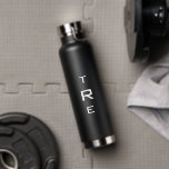 Bouteille D'eau Monogramme en gras sur noir<br><div class="desc">Le monogramme vertical blanc gras sur le noir présente une initiale plus grande au centre. Remplacez les 3 initiales par les vôtres dans la barre latérale. Autres couleurs et styles de bouteilles d'eau disponibles dans la barre latérale. Copyright © Claire E. Skinner. Tous droits réservés.</div>