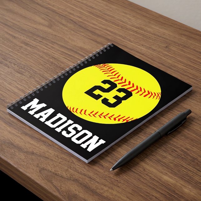 Carnet Softball personnalisé (Personalized softball notebook with custom name and number on a desk.)