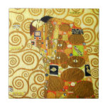Carreau Tuile de réalisation de Gustav Klimt<br><div class="desc">Tuile de réalisation de Gustav Klimt. Frise à partir de 1909. Accompli pendant la phase d'or de Klimt, la réalisation comporte un couple d'embrassement se tenant sous un édredon multi-modelé comportant des spirales, des yeux, des oiseaux, des poissons et d'autres formes. L'arrière - plan du travail comporte les mêmes spirales...</div>