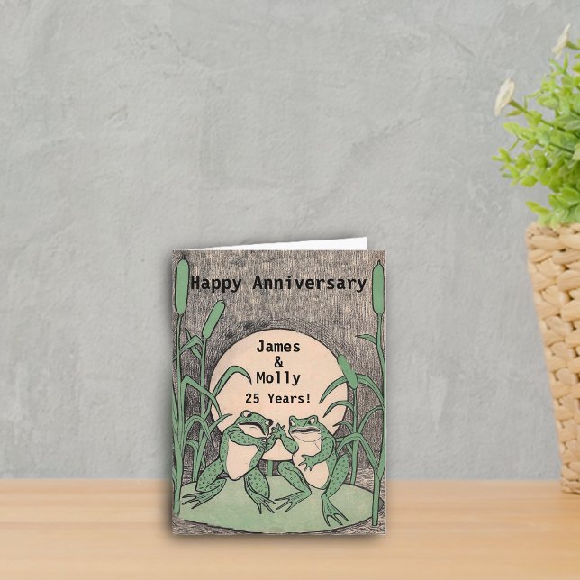 Carte 25ème lune heureuse de protection de lis de (Two cute argueing green frogs on lily pad full moon on Happy anniversary card.)