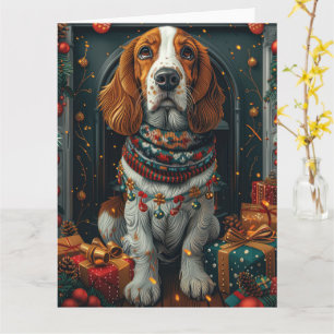 Carte Basset Hound avec des cadeaux de Noël devant une c