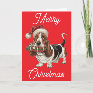 Carte Basset Hound avec un chapeau de Père Noël tenant u