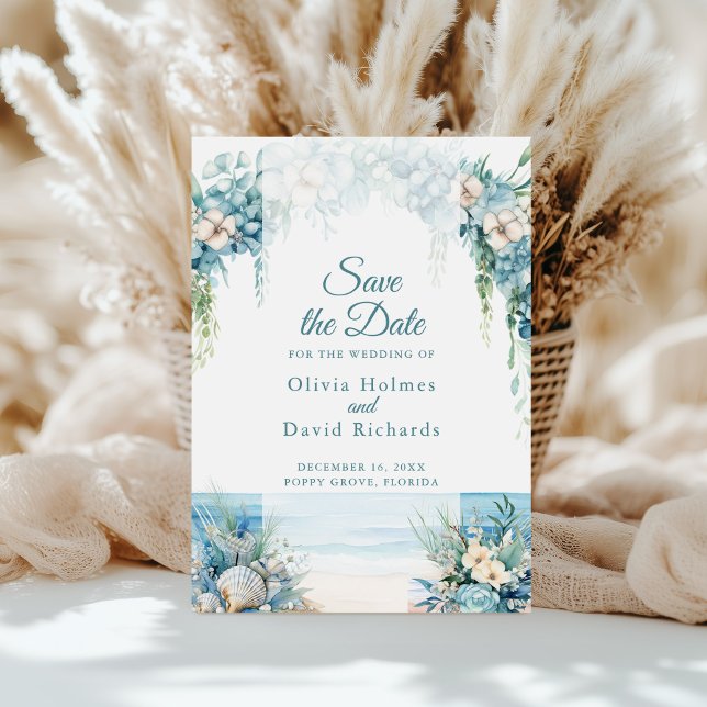 Carte de mise en garde de plage à l'arche florale  (Boho Blue Floral Arch Beach Save the Date Card on a sunny table in front of white pampas grass)