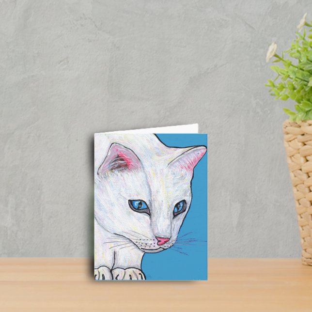 Carte de note blanche de chat d'yeux bleus (White cat with vibrant blue eyes on blue notecard.)