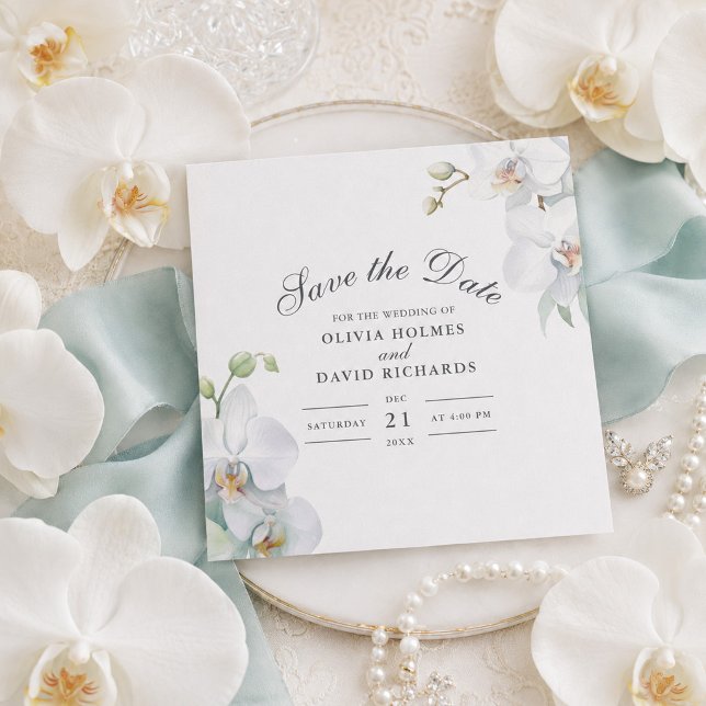 Carte de rappel moderne élégante à orchidée blanch (Modern Elegant White Orchid Save the Date Card on a table with white orchids)