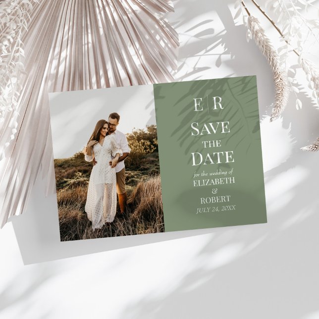 Carte de rendez-vous de sauvegarde de monogramme d (Modern Olive Monogram Photo Save the Date Card on a sunny white table with neutral dry botanicals.)
