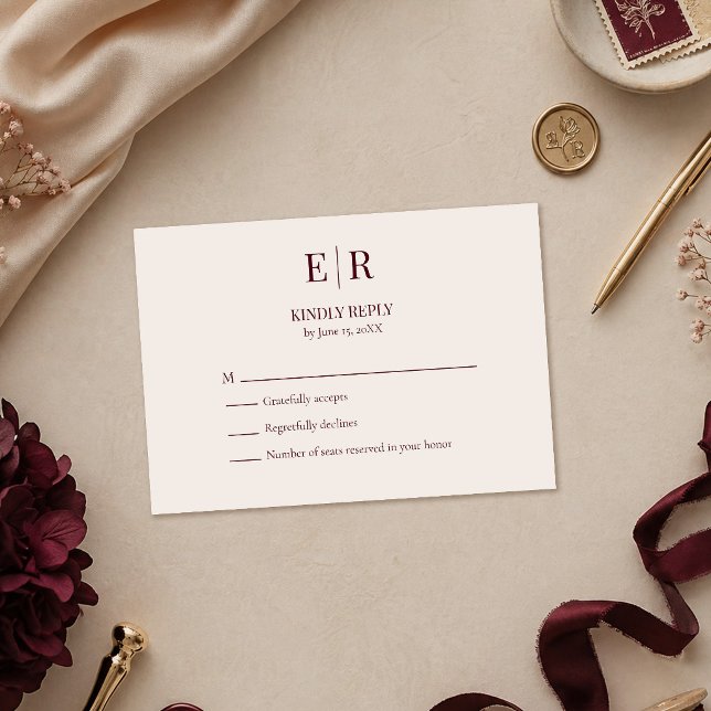 Carte de réponse de mariage élégante avec monogram (Elegant Burgundy Monogram Wedding RSVP Card on a table with burgundy and gold wedding decoration)