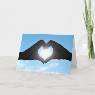 Carte Mains en forme de cœur en silhouette sur ciel bleu