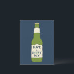 Carte Postale Bouteille de bière verte pour une journée à houblo<br><div class="desc">Cette carte postale est parfaite pour envoyer un message joyeux (ou plutôt, houblonné) à votre amateur de bière préféré. Elle présente une illustration d'une bouteille de bière en verre vert avec une étiquette couleur crème sur fond bleu marine. L'étiquette de la bouteille de bière indique HAVE A HOPPY DAY en...</div>