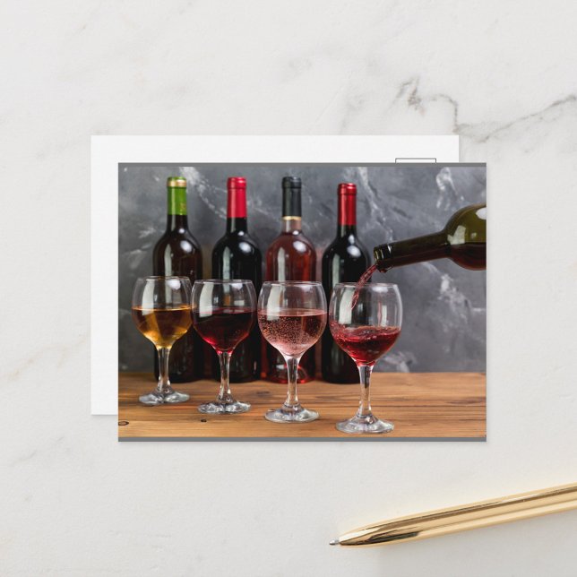 Carte Postale Bouteilles à vin (A hand pours red wine into a glass, with a row of wine bottles in the background!)
