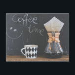 Carte Postale Café avec de la boue et du pot<br><div class="desc">Un tableau à pattes à l'arrière indique "café time" avec un visage souriant, écrit à la craie. A l'avant sur une table en bois rustique se trouve une tasse à café au design motif en diamant noir et blanc. À côté de la tasse de café se trouve une cafetière avec...</div>