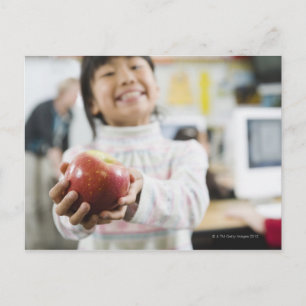 Carte Postale Étudiante élémentaire tenant une pomme dans la mai