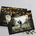 Carte Postale Faire-part Fleur d'hiver et bois de grange économisez la date<br><div class="desc">Fleurs crème blanches avec feuillage saisonnier et cordes rustiques de lumières scintillantes sur brun foncé élégant grange photo enregistrer la carte postale mariage date. Facile à personnaliser avec vos noms et votre texte ! Convient pour l'hiver fleuri, l'été ou l'automne / jardin de jardin rustique pays ou mariages à thème...</div>