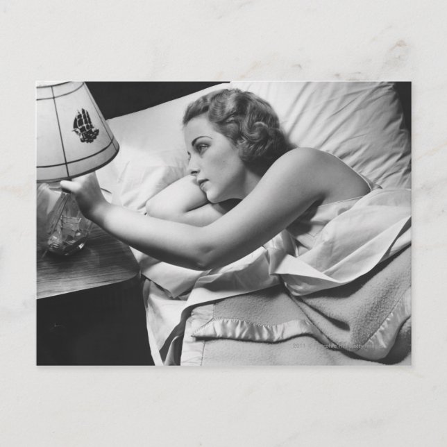 Carte Postale Jeune femme allongée sur le lit éteint la lampe (Devant)