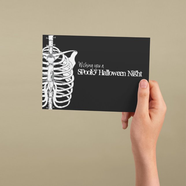 Carte Squelette effrayant Halloween Noir et Blanc (Spooky Halloween greeting card with skeleton illustration and gothic black background.)