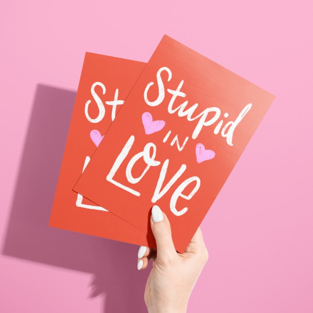 Carte « Stupide en amour avec toi juste parce que  (Bold red card with pink hearts and white lettering "stupid in love ... with you" and custom text)