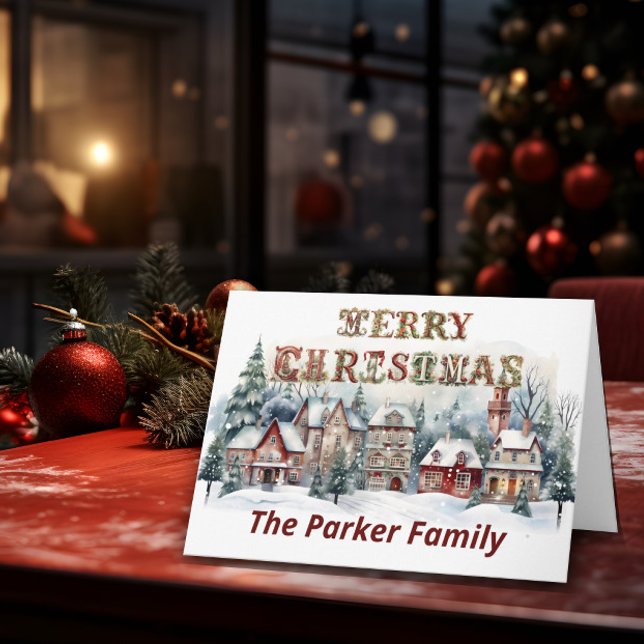 Carte Village victorien Joyeux Noël (A Christmas card stands on top of a table with Christmas elements in the background.)