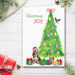 Cartes Pour Fêtes Annuelles Basset Hound Chien, Oiseau et Arbre de Noël<br><div class="desc">Sur le devant de cette carte de Noël, un heureux chien de Basset Hound porte un casquette de Père Noël rouge et blanc alors qu'il est assis à côté d'un arbre de Noël. Des emballages de cadeaux aux couleurs vives sont éparpillés, et un bullfinch débarque sur le sapin de Noël....</div>