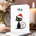 Cartes Pour Fêtes Annuelles Drôle noir assis Père Noël Chat de Noël<br><div class="desc">Montre un chat noir avec les yeux verts et la queue bouclée. Le chat porte un casquette du Père Noël rouge et a un ornement d'étoile de Noël suspendu de sa queue. Le texte ci-dessus se lit "Ho", qui est un "ho ho ho ho" peu enthousiaste. Customisez et personnalisez le...</div>