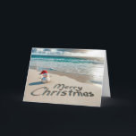 Cartes Pour Fêtes Annuelles Snowman de Noël tropical sur une plage<br><div class="desc">Un bonhomme de neige de sable portant un chapeau de Père Noël se dresse sur une plage de sable avec "Joyeux Noël" écrit dans le sable</div>