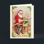Cartes Pour Fêtes Annuelles Vintage Santa Christmas<br><div class="desc">This adorable image of Santa sitting down in his workshop painting was scanned from an vintage — antique actually — postcard. Santa is holding brushes and a palette while the paints the roof a dollhouse. this image is framed with holly and mistletoe branches.</div>