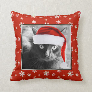 Chat de Noël sur le coussin rouge avec des flocons