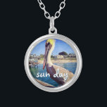 Collier Sun Day Ocean Beach Pier Pelican Bird Photo mignon<br><div class="desc">"Jour du soleil." Ce pélican mignon et heureux perché sur une rampe surplombant une plage californienne crie "prêt pour les vacances". Retournez à la brise chaude de l'océan chaque fois que vous portez ce collier de charme photographique coloré. Ce collier se présente en petites, moyennes et grandes tailles, ainsi qu'en...</div>
