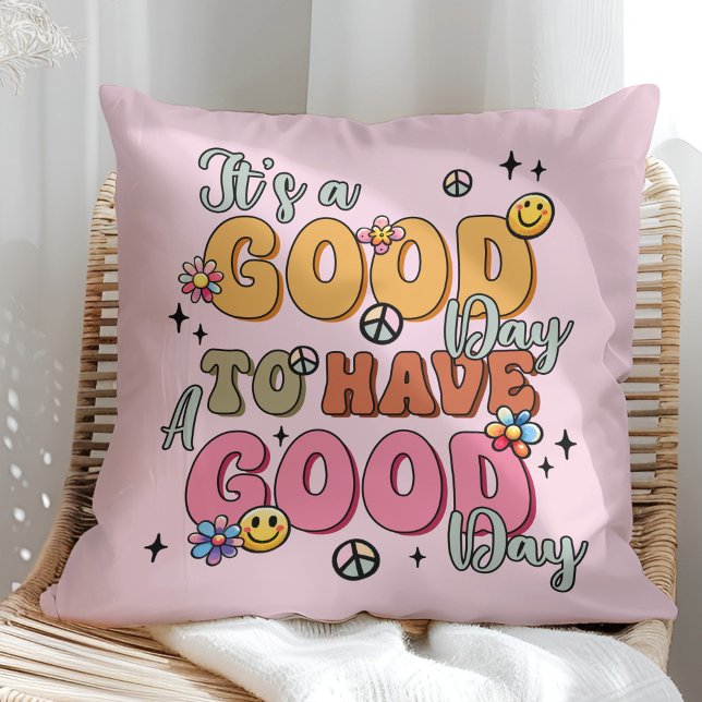 Coussin "C'est une Bonne Journée" Couleur Rétro Positivité ("It's a Good Day" Retro Colorful Positivity Throw Pillow on a sunny boho rattan chair.)