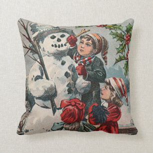 Coussin Enfants faisant un bonhomme de neige au houx