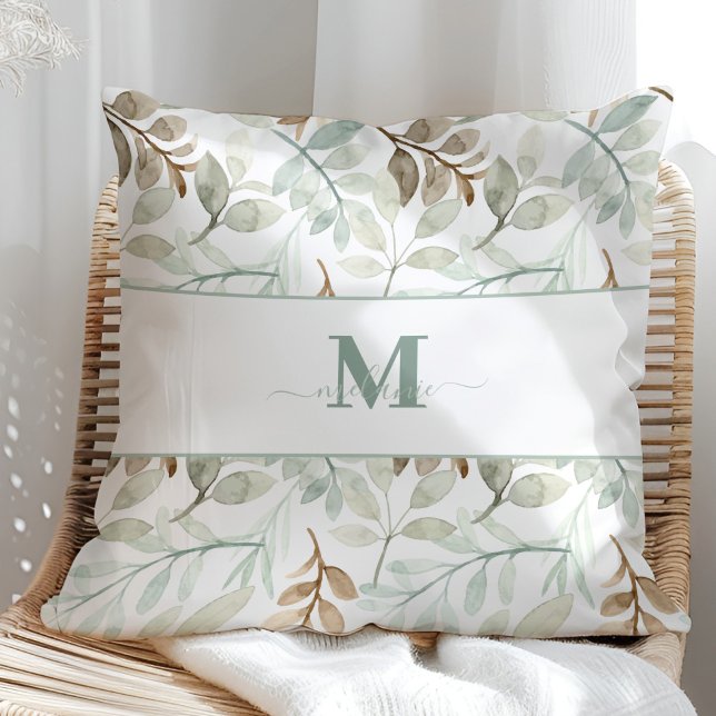 Coussin Feuilles d'aquarelle avec nom personnalisé et init (Watercolor leaves with Custom Name and Initial Throw Pillow in a sunny rattan armchair.)