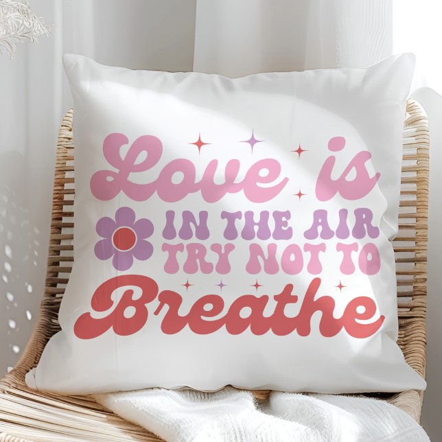 Coussin L'amour est dans l'Air Funny Anti Valentine (Love is in the Air Funny Anti Valentine Throw Pillow on a sunny rattan chair.)