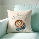 Coussin L'Amour Thématique De L'Amateur De Café Est En Tra<br><div class="desc">Ajoutez une touche cosy à votre maison ou à votre événement avec notre oreiller à thème pour amateurs de café, avec la phrase charmante "L'amour brasse" à côté de l'art de la maison de café illustrée. Un cadeau charmant pour les amateurs de café, ce coussin apporte chaleur et style à...</div>