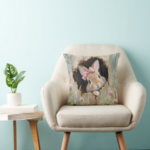 Coussin Lapin avec noeud rose dans un trou de clôture