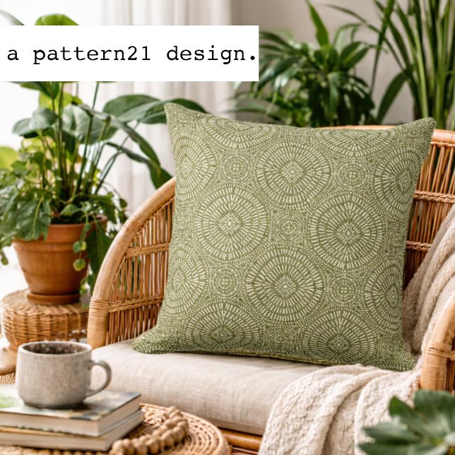 Coussin motif vert bohème (Olive geometric accent pillow styled in a bright plant-filled living space.)