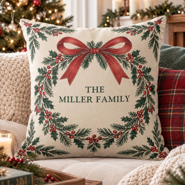 Coussin Noeud de ruban de houx traditionnel avec nom de fa (Custom family name holiday pillow featuring a traditional holly wreath design with a large red bow.)